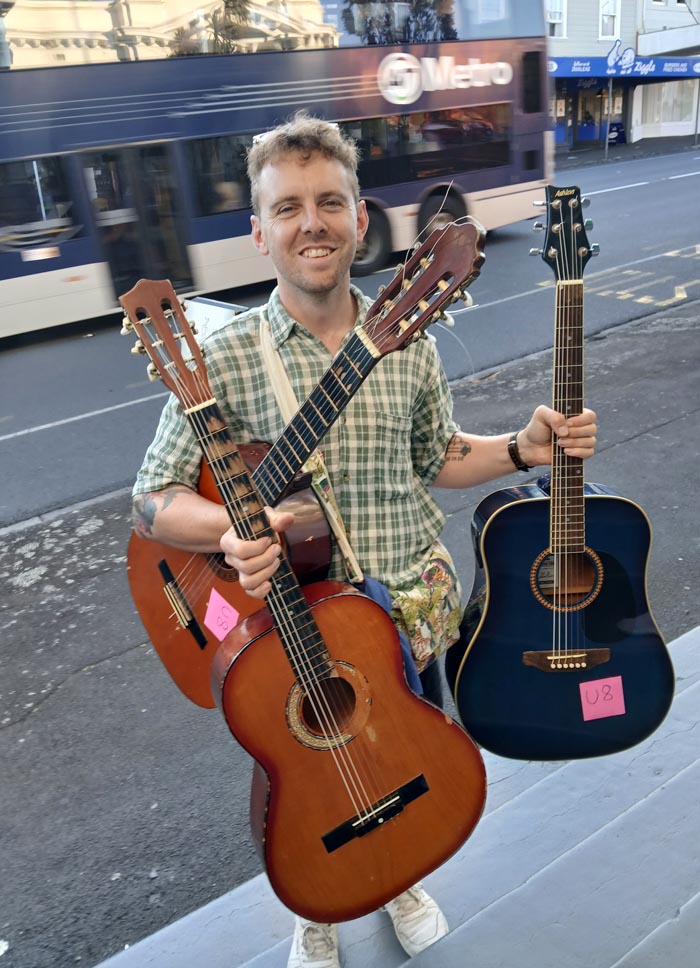 Benjamin Sinclair holding three guitars he has fixed